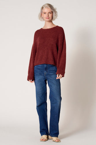 Vrouw in rode trui en blauwe jeans.