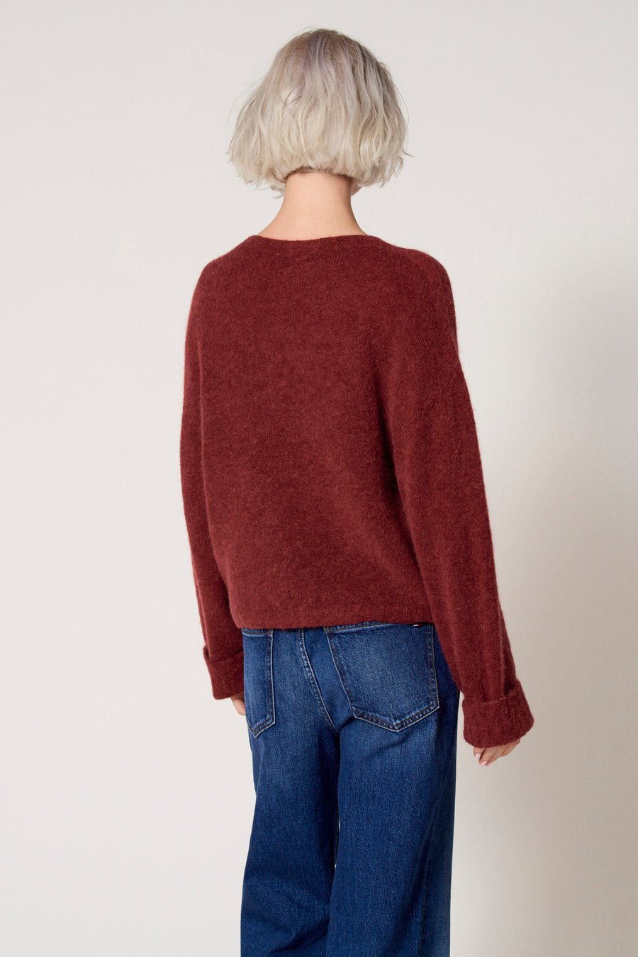 Achterkant van vrouw in rode trui en blauwe jeans.