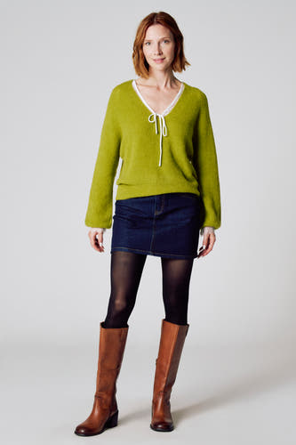 T-shirt V-hals vert de Cloudss Fashion, avec longues manches et un détail ce ceord, associé à une jupe en denim, un string et des bottes brunes.