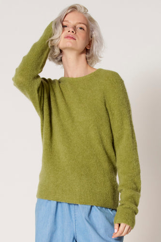 Vrouw met groene trui en blauwe broek.
