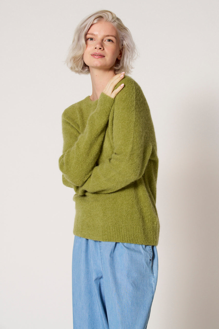 Vrouw met groene trui en blauwe broek.