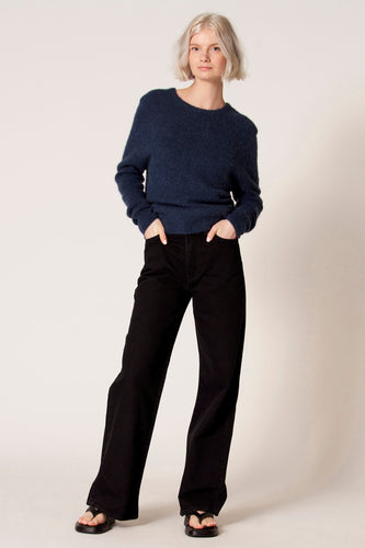 Vrouw in blauwe trui en zwarte broek.