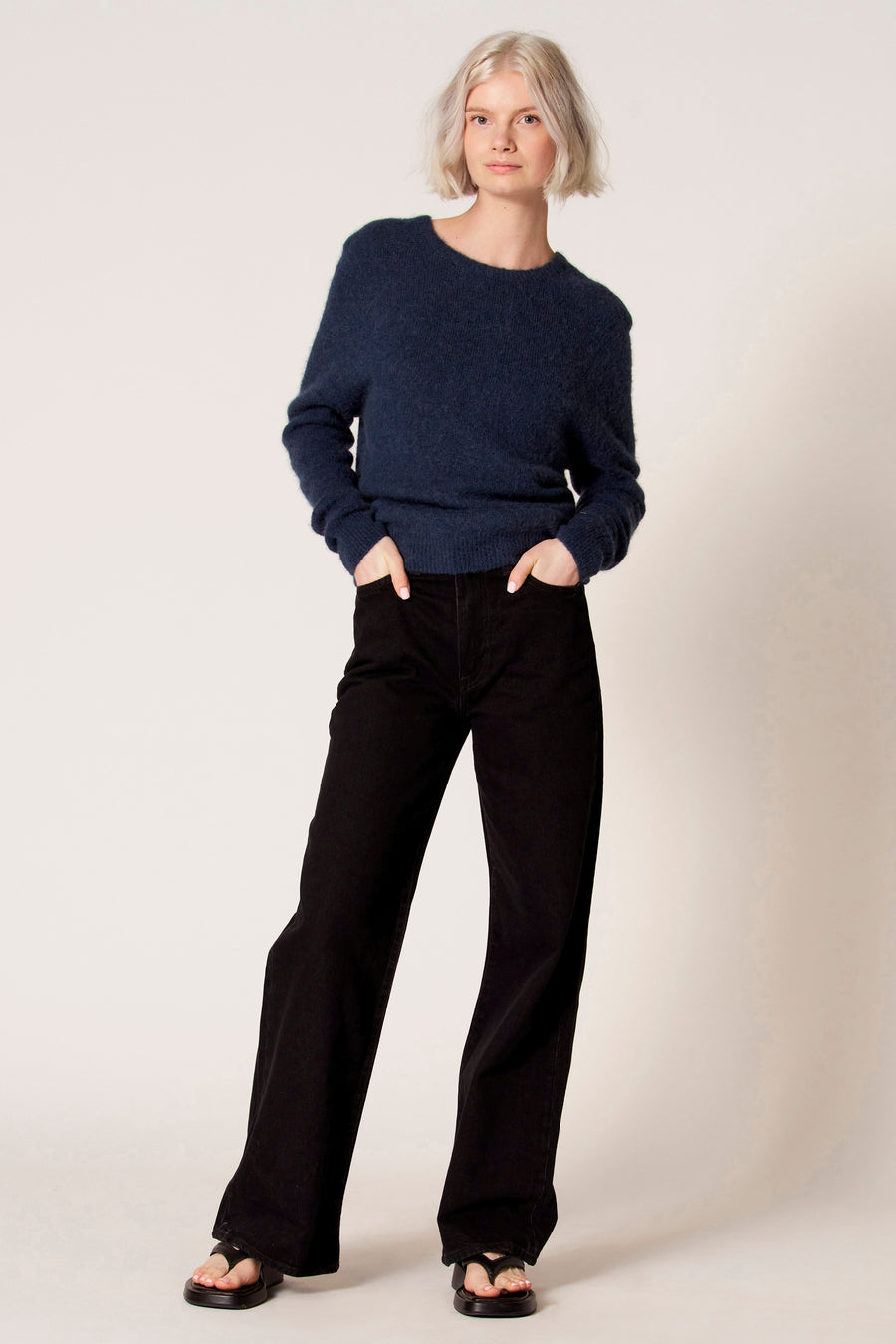 Vrouw in blauwe trui en zwarte broek.