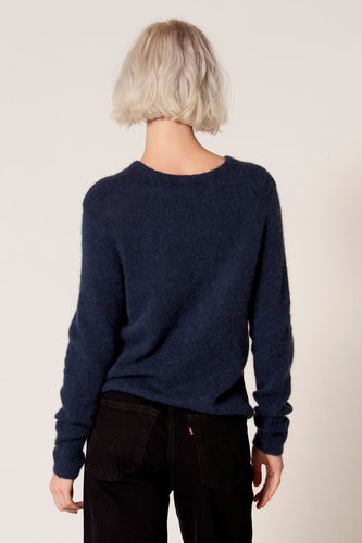 Vrouw van achteren in donkerblauwe trui en zwarte jeans.