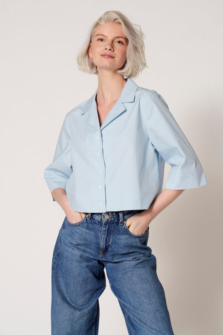 Chemisier bleu à manches trois-quarts de Clouds of Fashion, porté avec un jean à jambes larges.