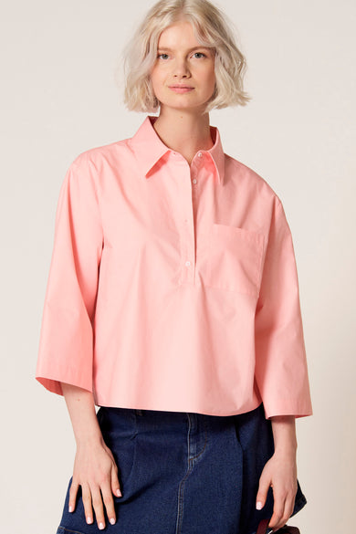 Chemisier rose à manches trois-quarts de Clouds of Fashion, avec une poche poitrine et porté avec une jupe bleu foncé.