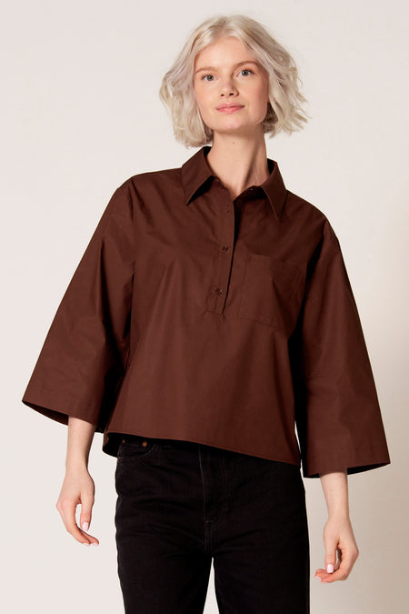Chemisier marron à manches trois-quarts de Clouds of Fashion, avec une fermeture boutonnée et une poche poitrine, combiné avec un jean noir.
