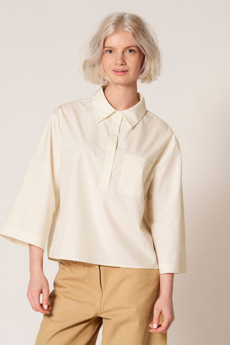 Chemisier blanc de Clouds of Fashion avec manches trois-quarts et une poche poitrine, combiné avec un pantalon marron.