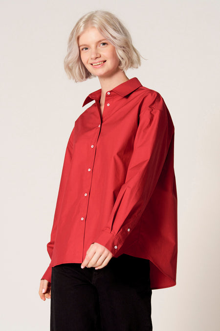 Chemisier rouge à manches longues de Clouds of Fashion, avec boutons blancs et porté avec un pantalon noir.