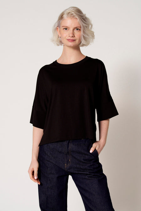 Zwart T-shirt met korte mouwen van Clouds of Fashion, gedragen met donkerblauwe jeans.