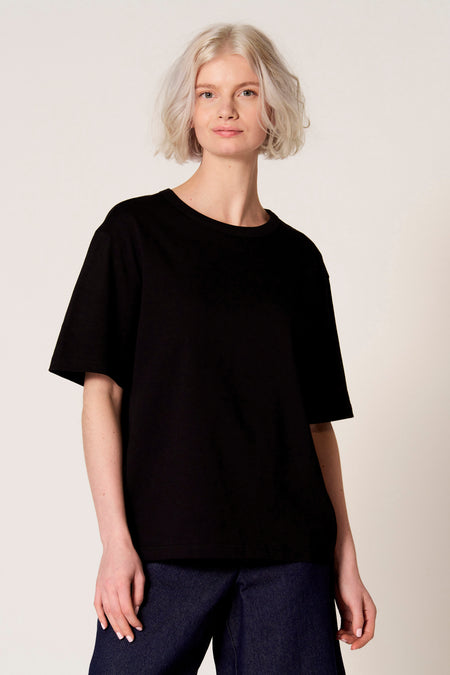 Zwart T-shirt met korte mouwen van Clouds of Fashion, gedragen met een donkerblauwe broek.