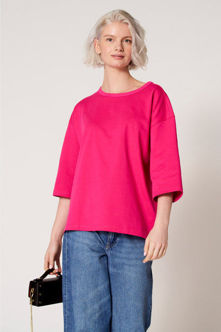 Roze T-shirt met korte mouwen van Clouds of Fashion, met een losse pasvorm en gecombineerd met blauwe jeans en een zwarte handtas.