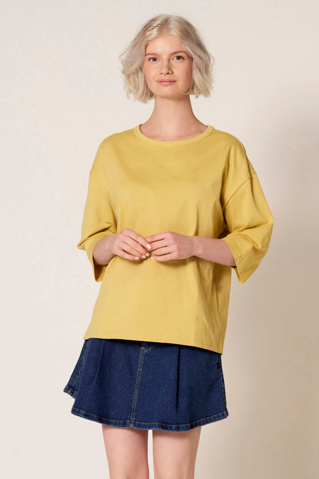 Geel T-shirt met korte mouwen van Clouds of Fashion, gecombineerd met een donkerblauwe denim rok.