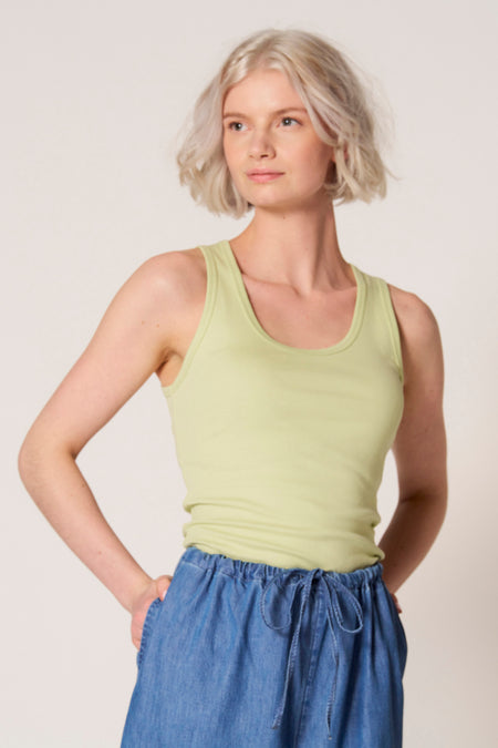 Groene singlet van Clouds of Fashion, gedragen met een blauwe broek met trekkoord.
