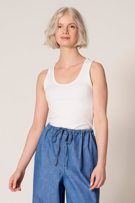 Witte singlet van Clouds of Fashion, gedragen met blauwe broek met trekkoord.
