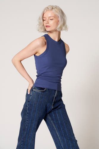 Débardeur bleu de Clouds of Fashion, avec un col rond, porté avec un jean bleu à rayures.