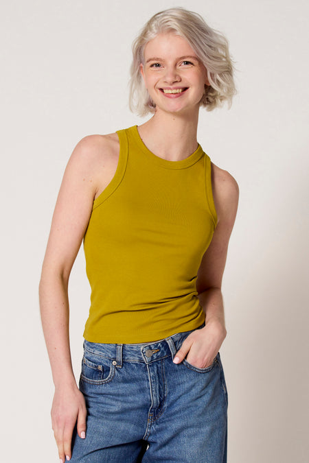 Groene singlet van Clouds of Fashion, gedragen met een jeans met zakken, tegen een witte achtergrond.
