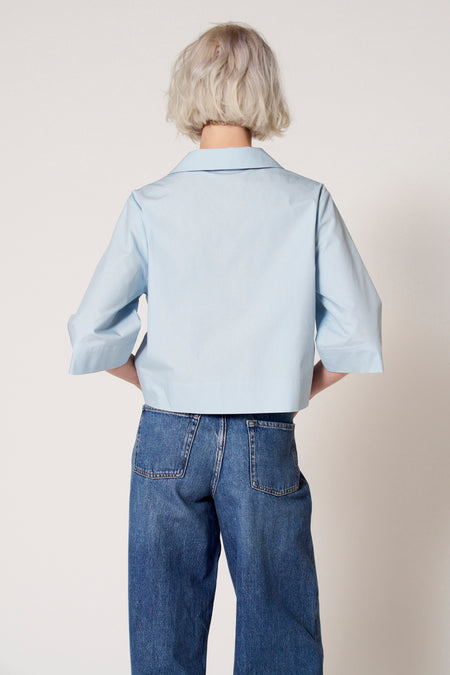 Blouse bleue à manches trois-quarts de Clouds of Fashion, avec un col et associée à des jeans larges.