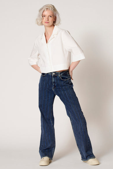 Chemisier blanc à manches trois-quarts de Clouds of Fashion, avec un col et combiné avec un jean à rayures bleues.