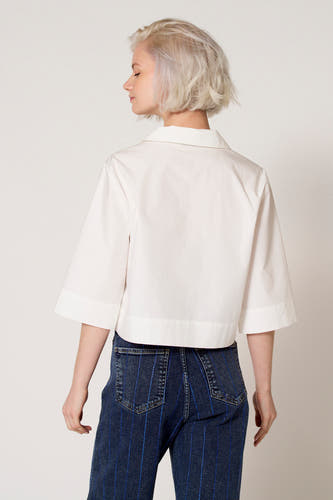 Chemisier blanc à manches trois-quarts de Clouds of Fashion, avec une coupe droite et porté avec un jean bleu.