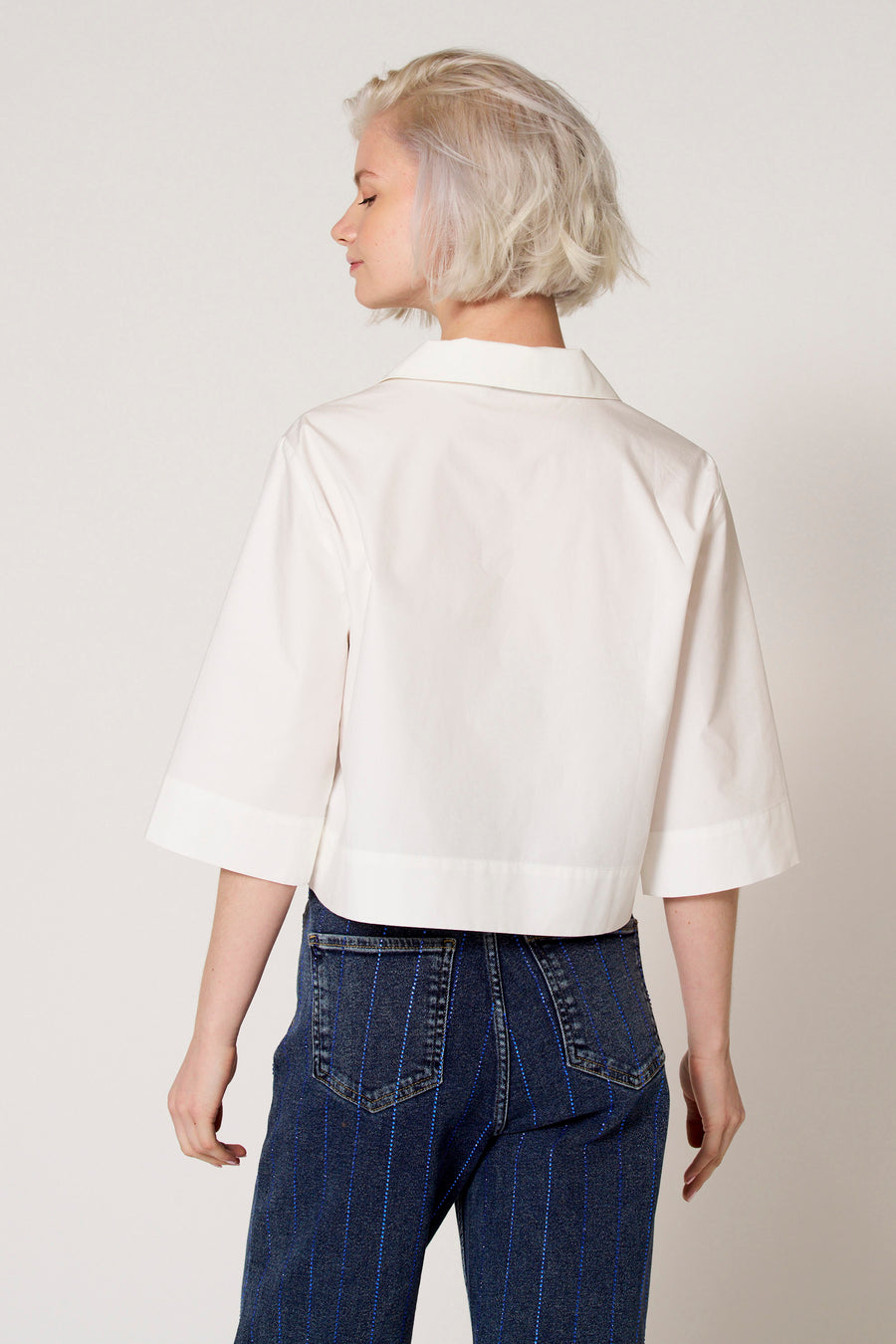 Chemisier blanc à manches trois-quarts de Clouds of Fashion, avec une coupe droite et porté avec un jean bleu.