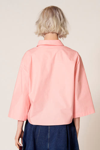 Blouse rose à manches trois-quarts de Clouds of Fashion, vue de derrière avec une jupe bleu foncé.