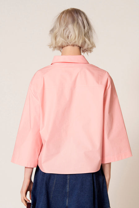 Blouse rose à manches trois-quarts de Clouds of Fashion, vue de derrière avec une jupe bleu foncé.