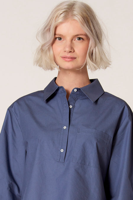 Blouse bleue de Clouds of Fashion avec une poche poitron et des boutons blancs.