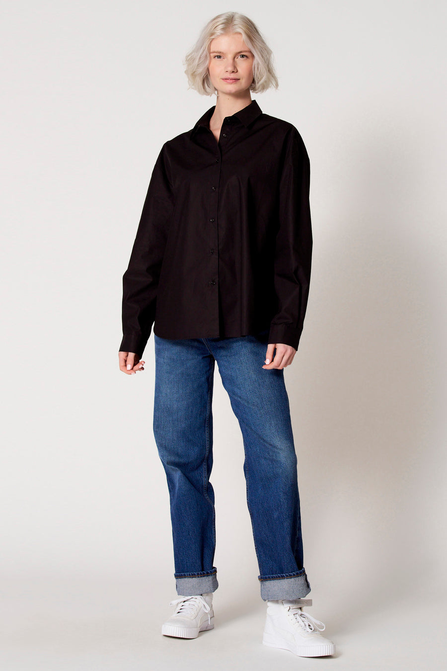Blouse noire à manches longues de Clouds of Fashion, portée avec des jeans.