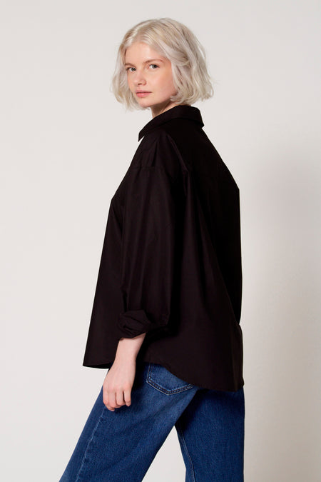 Zwarte blouse met lange mouwen van Clouds of Fashion, gedragen met jeans.
