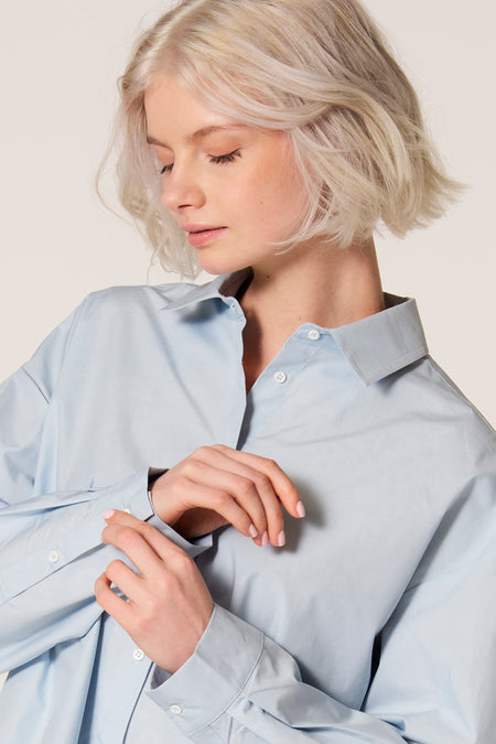 Blauw blouse met lange mouwen van Clouds of Fashion, gedragen door een vrouw met blonde haren.
