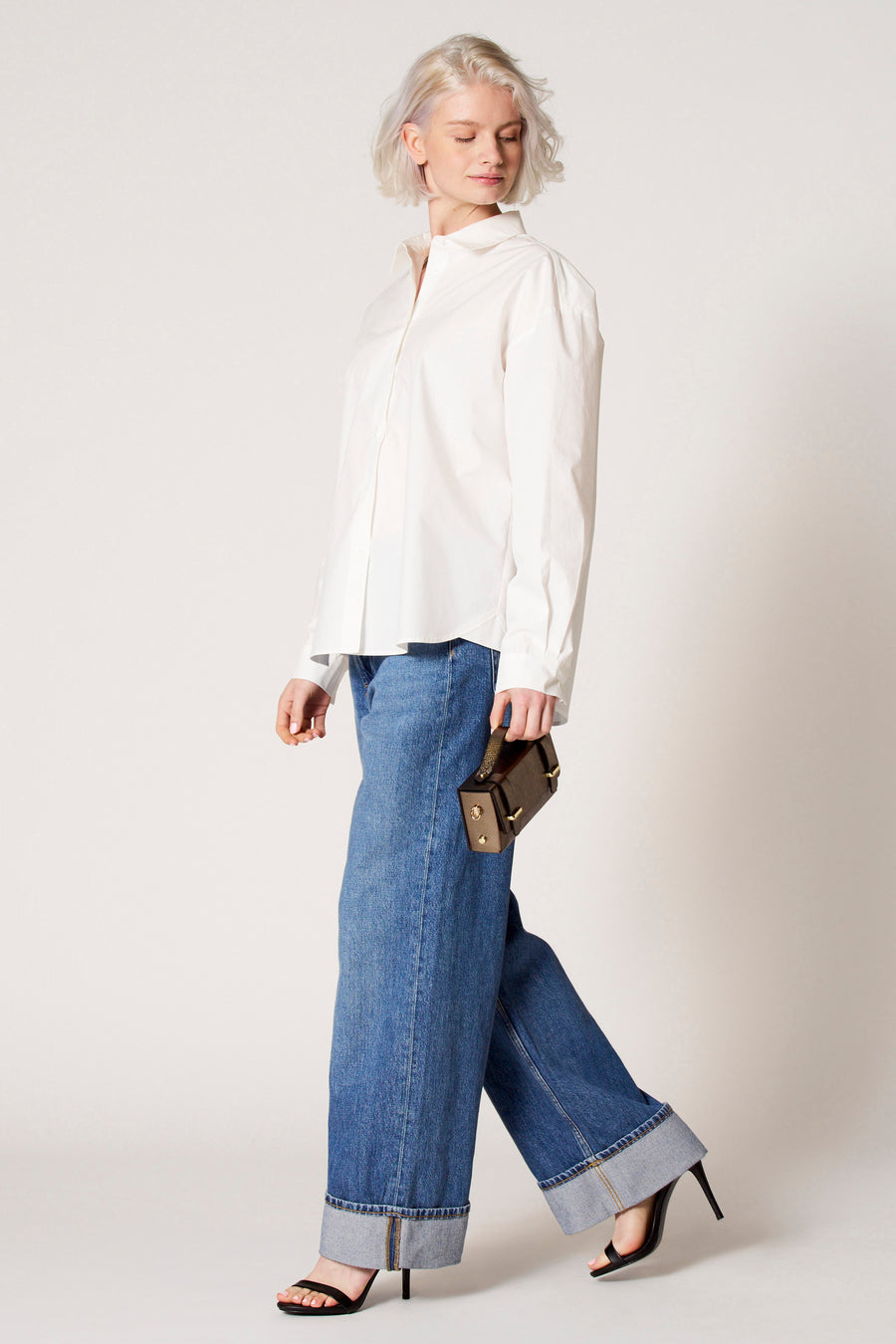 Blouse blanche à longues manches de Clouds of Fashion, portée avec un jeans large et une sac marron.