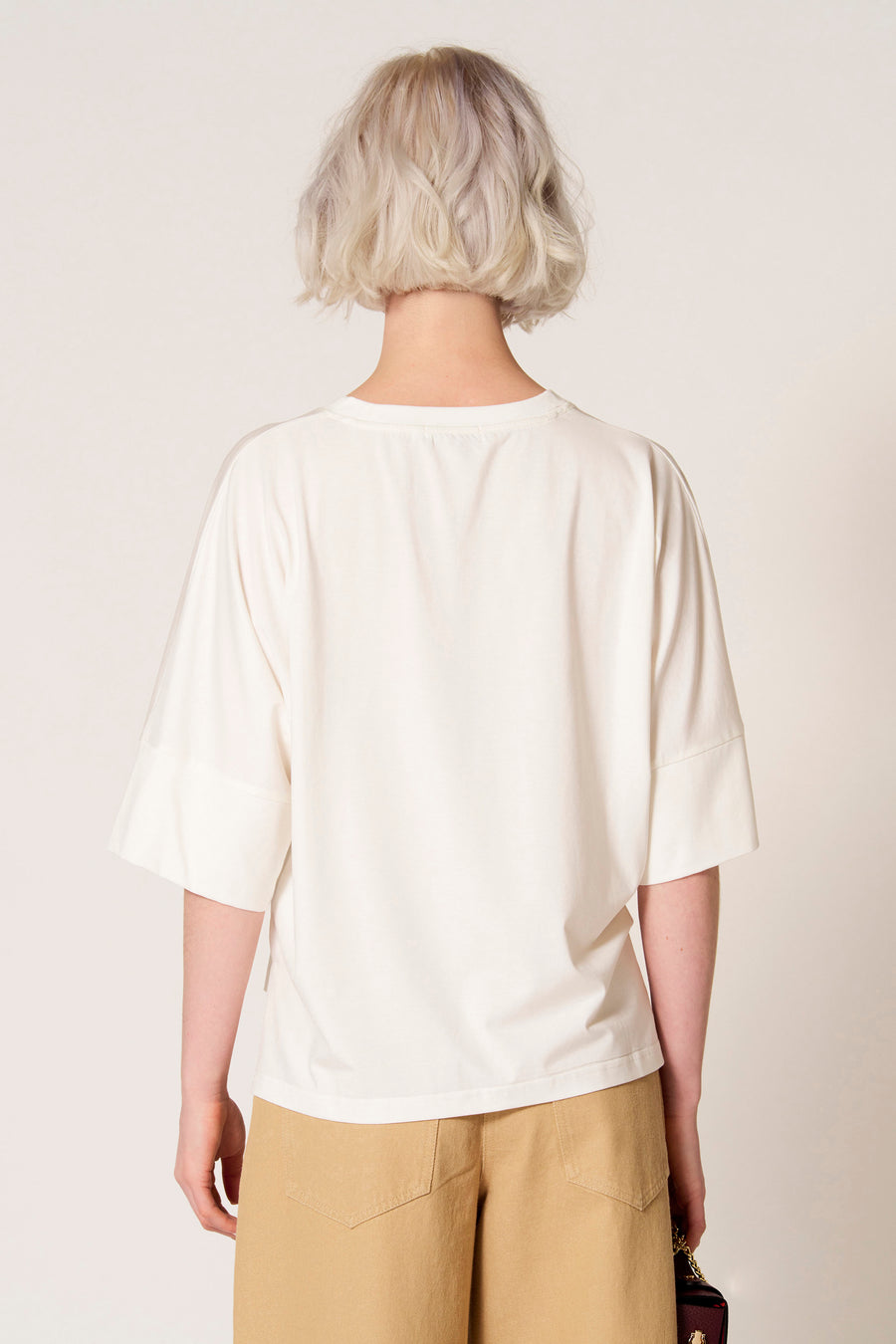 T-shirt écru à manches courtes de Clouds of Fashion, vu de dos, combiné avec un pantalon kaki.