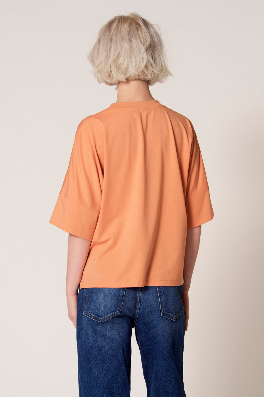 Oranje T-shirt met korte mouwen van Clouds of Fashion, gezien van achteren, met een effen kleur en gecombineerd met een jeans.