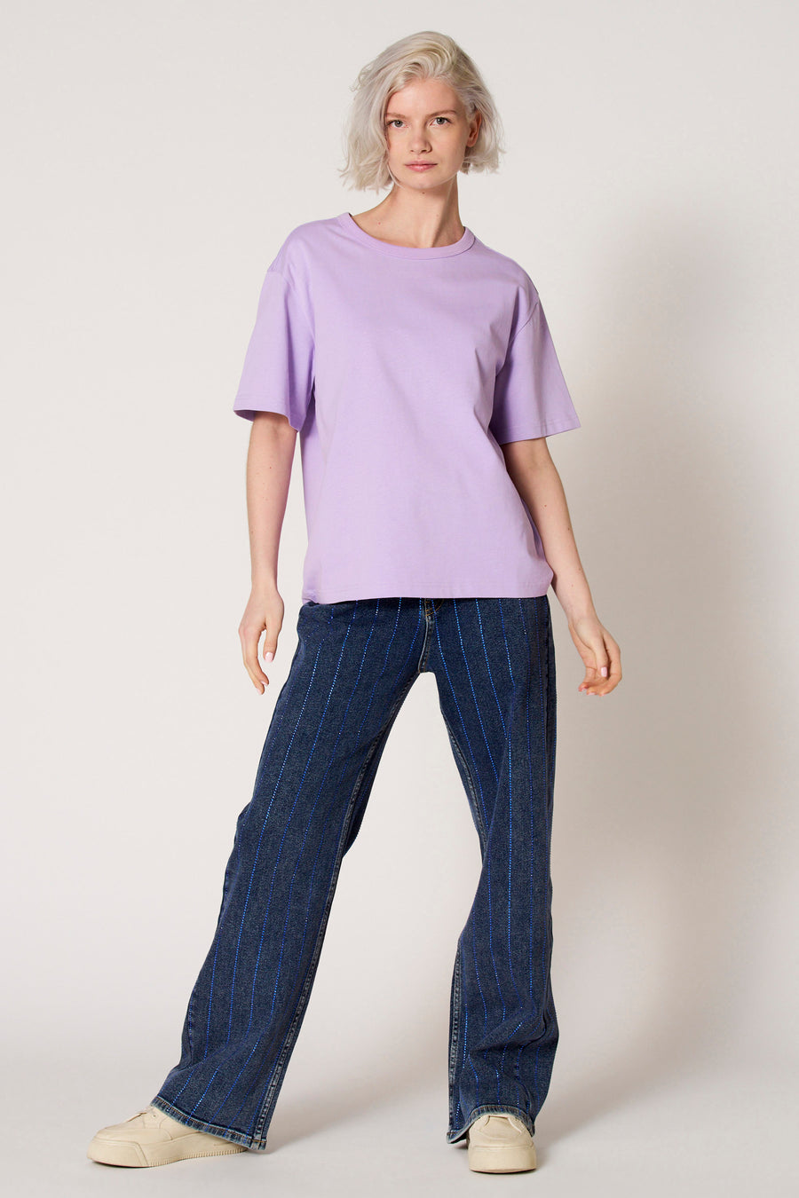 T-shirt à manches courtes violet de Clouds of Fashion, de couleur unie, associé à un jean à rayures verticales.
