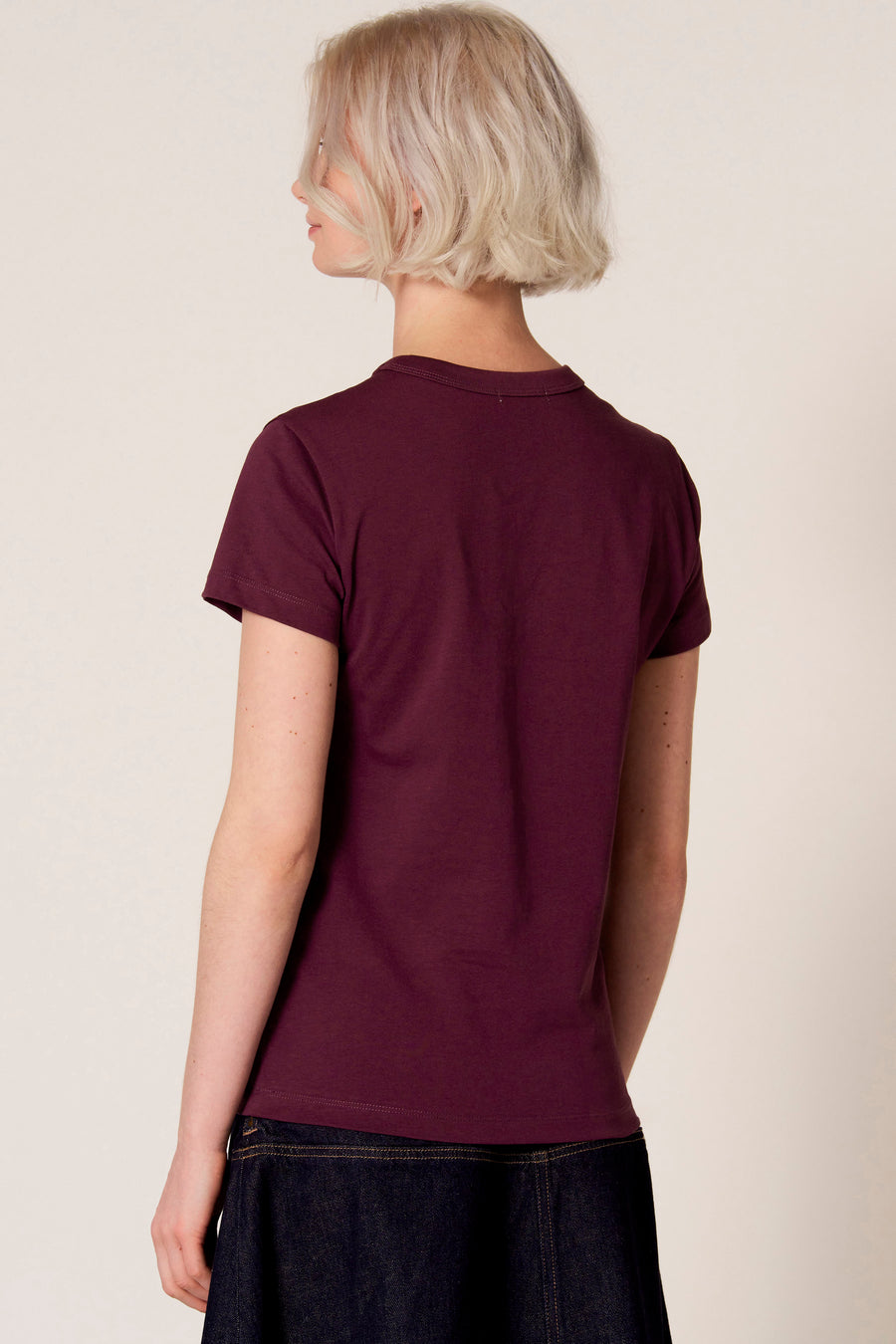 Paars T-shirt met korte mouwen van Clouds of Fashion, gezien van achteren, gecombineerd met een donkerblauwe rok.
