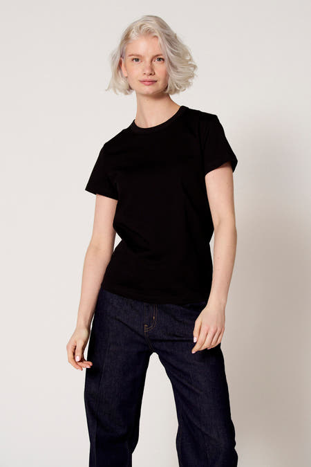 Zwart T-shirt met korte mouwen van Clouds of Fashion, gedragen met een donkere denim broek en een effen achtergrond.