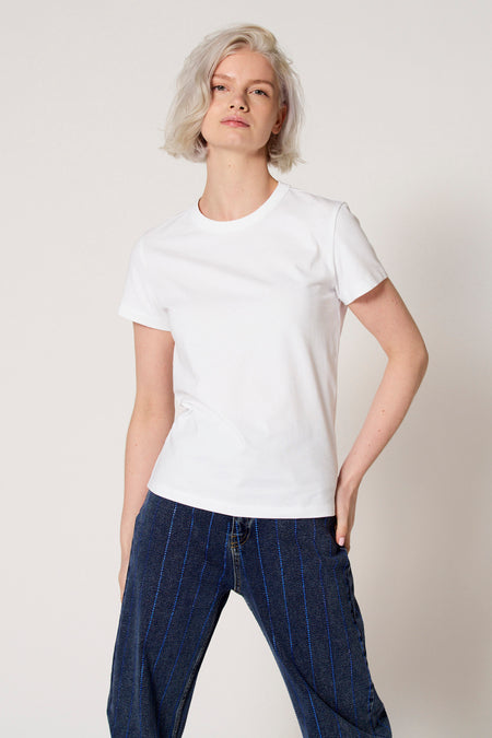 Wit T-shirt met korte mouwen van Clouds of Fashion, gedragen met een blauwe broek met krijtstreep.