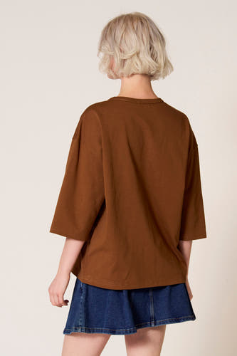 Bruin T-shirt met korte mouwen van Clouds of Fashion, gezien van achteren, gecombineerd met een denim rok.
