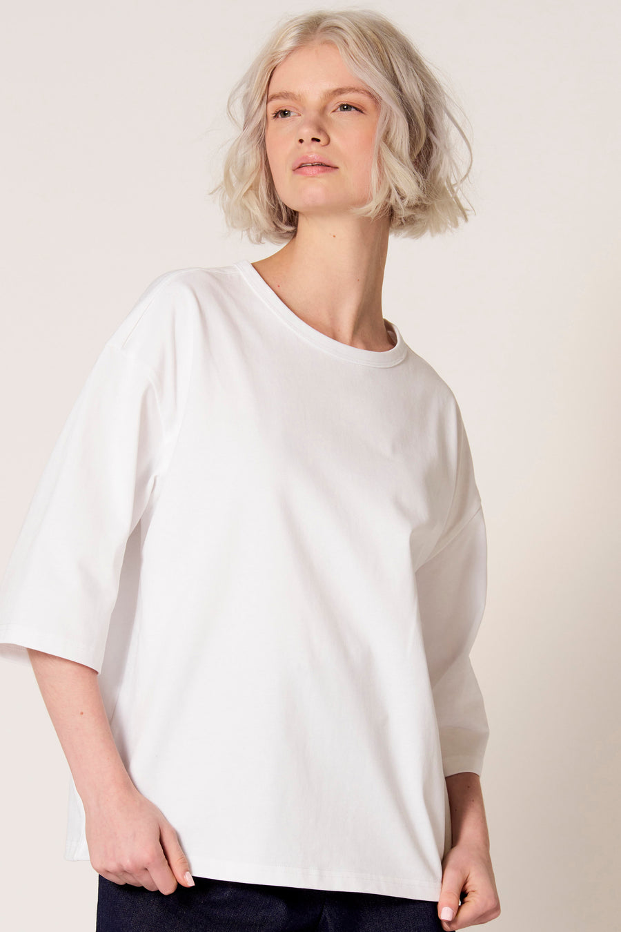 T-shirt blanc à manches courtes de Clouds of Fashion, porté avec un pantalon foncé.