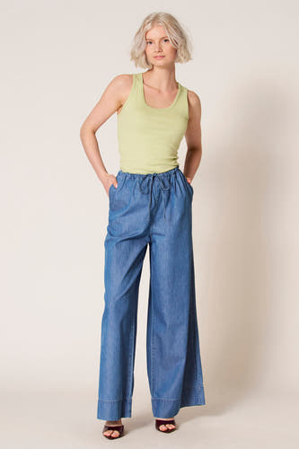 Débardeur vert de Clouds of Fashion, avec encolure ronde, porté avec un pantalon ample en jean bleu.