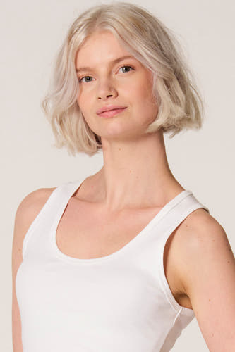 Débardeur blanc de Clouds of Fashion, porté par une femme avec une coupe au carré sur un fond uni.