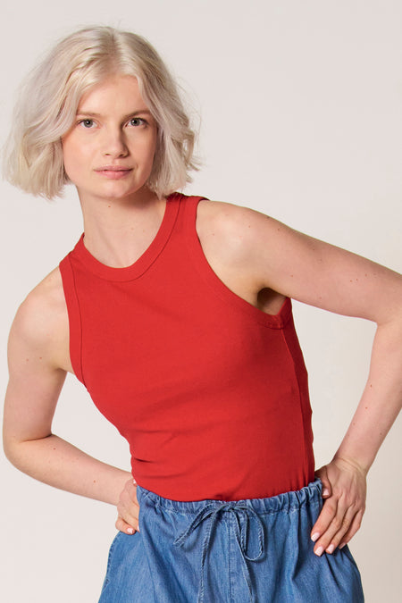 Rode singlet van Clouds of Fashion, met een ronde halslijn, gecombineerd met een blauwe broek met een elastische tailleband.
