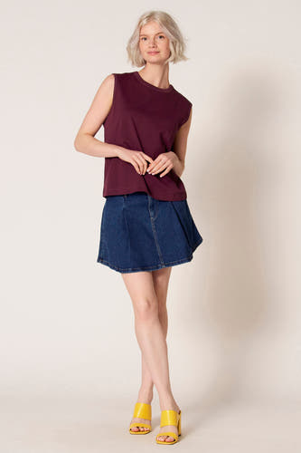 Débardeur violet de Clouds of Fashion, porté avec une jupe en jean bleu et un sourire fermé.