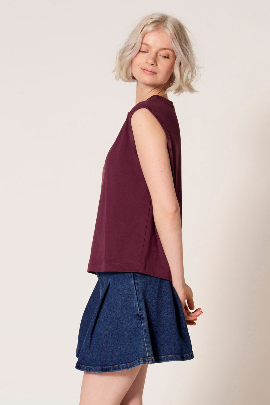 Paarse singlet van Clouds of Fashion, gedragen met een blauwe denim rok en een gesloten glimlach.
