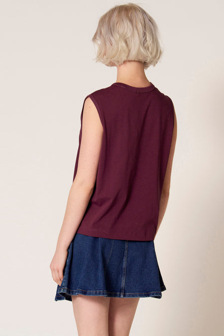 Paarse singlet van Clouds of Fashion, met afgewerkte armsgaten, gecombineerd met een korte denim rok, gezien van achteren.
