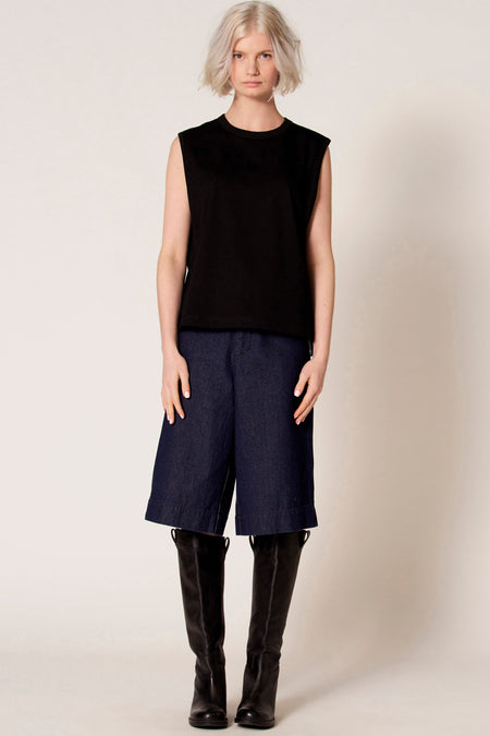 Zwarte singlet van Clouds of Fashion, gedragen met donkerblauwe culottes en zwarte leren kniehoge laarzen.