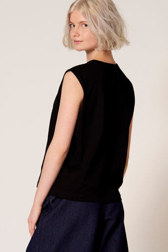 Débardeur noir de Clouds of Fashion, avec une coupe décontractée et associé à un pantalon bleu foncé.