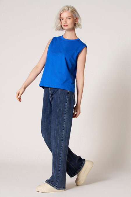 Blauwe singlet van Clouds of Fashion, gecombineerd met gestreepte jeans en crèmekleurige sneakers.
