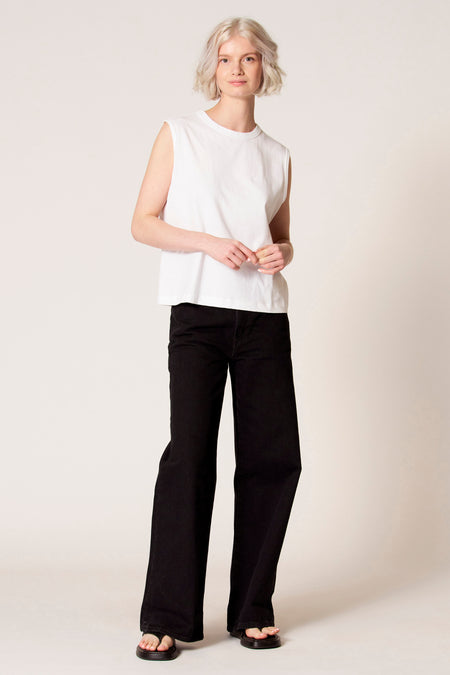 Witte singlet van Clouds of Fashion, gedragen met zwarte jeans en sandalen.